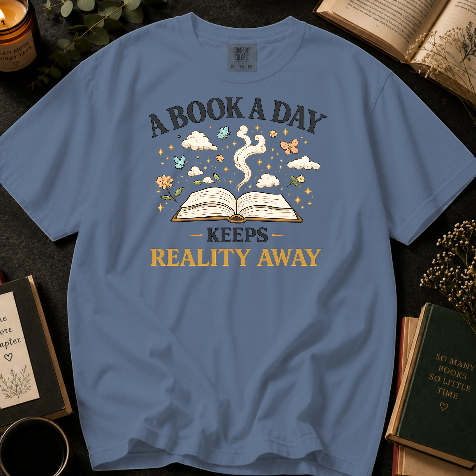 A Book A Day Keeps Reality Away T-Shirt: Whimsical Open Book in Blue Jean - Comfort Colors® T-Shirt